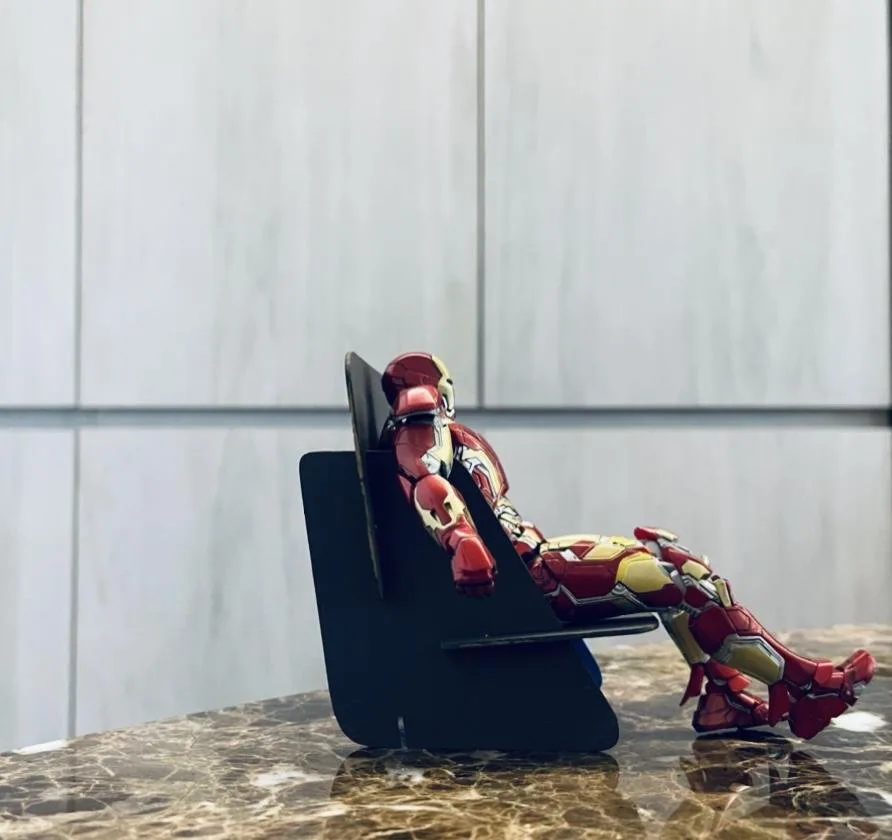 Low-angle side view of the scale model chair, with an Iron Man action figure reclining against the angled backrest.