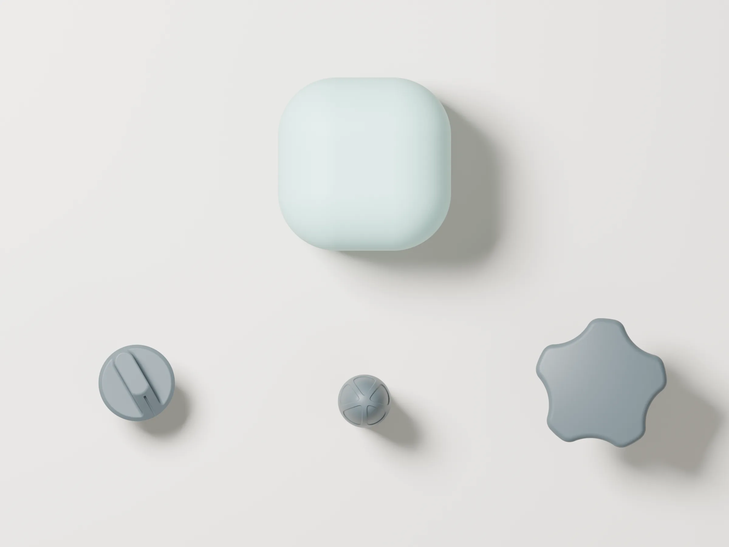 Top-down flat lay of the Version 1 kit: the rounded mint cube above three grey knobs seen from above — a disc with a pointer fin, a small domed knob and a five-lobed knob.