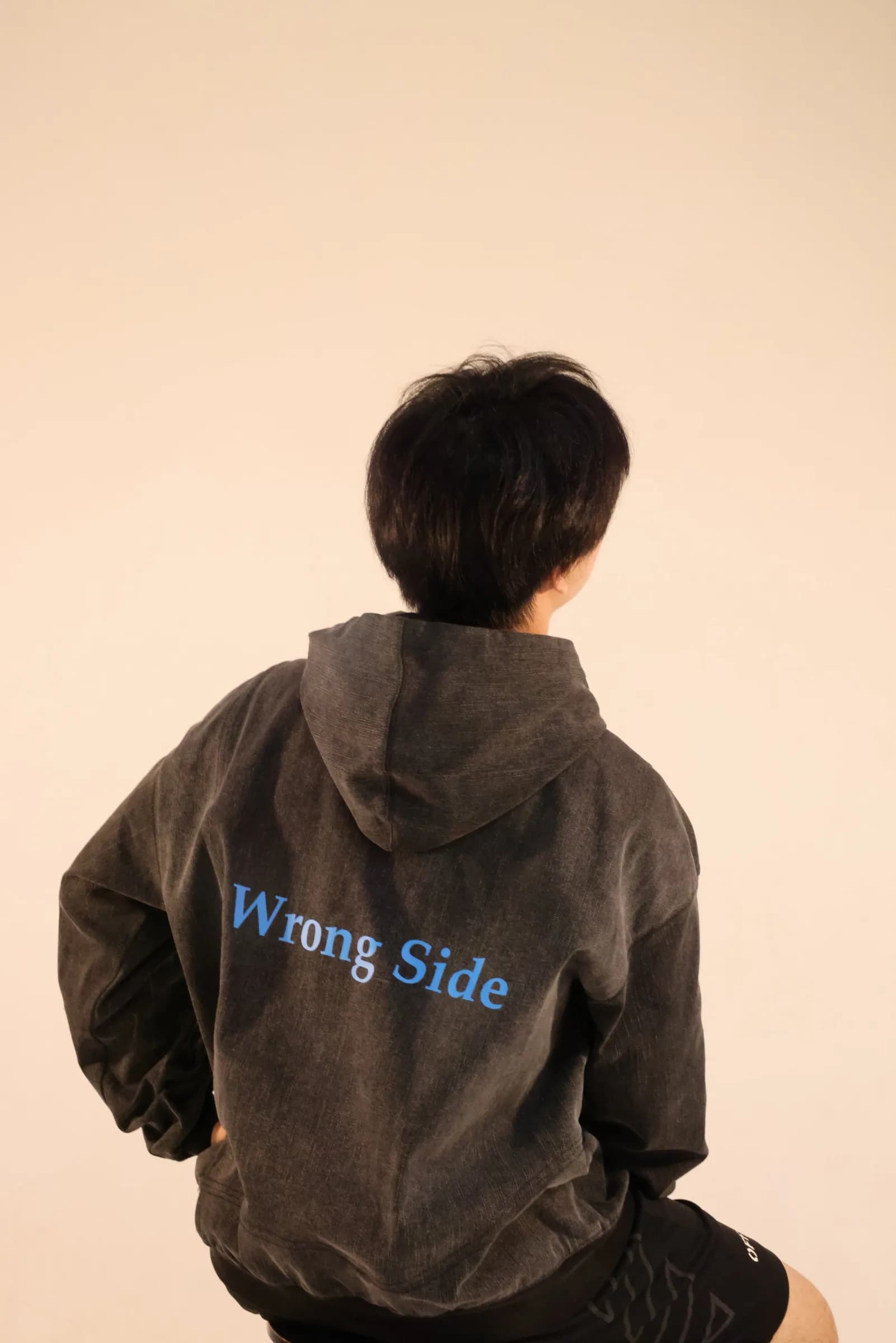 Model seen from behind wearing the denim hoodie with “Wrong Side” printed on the back