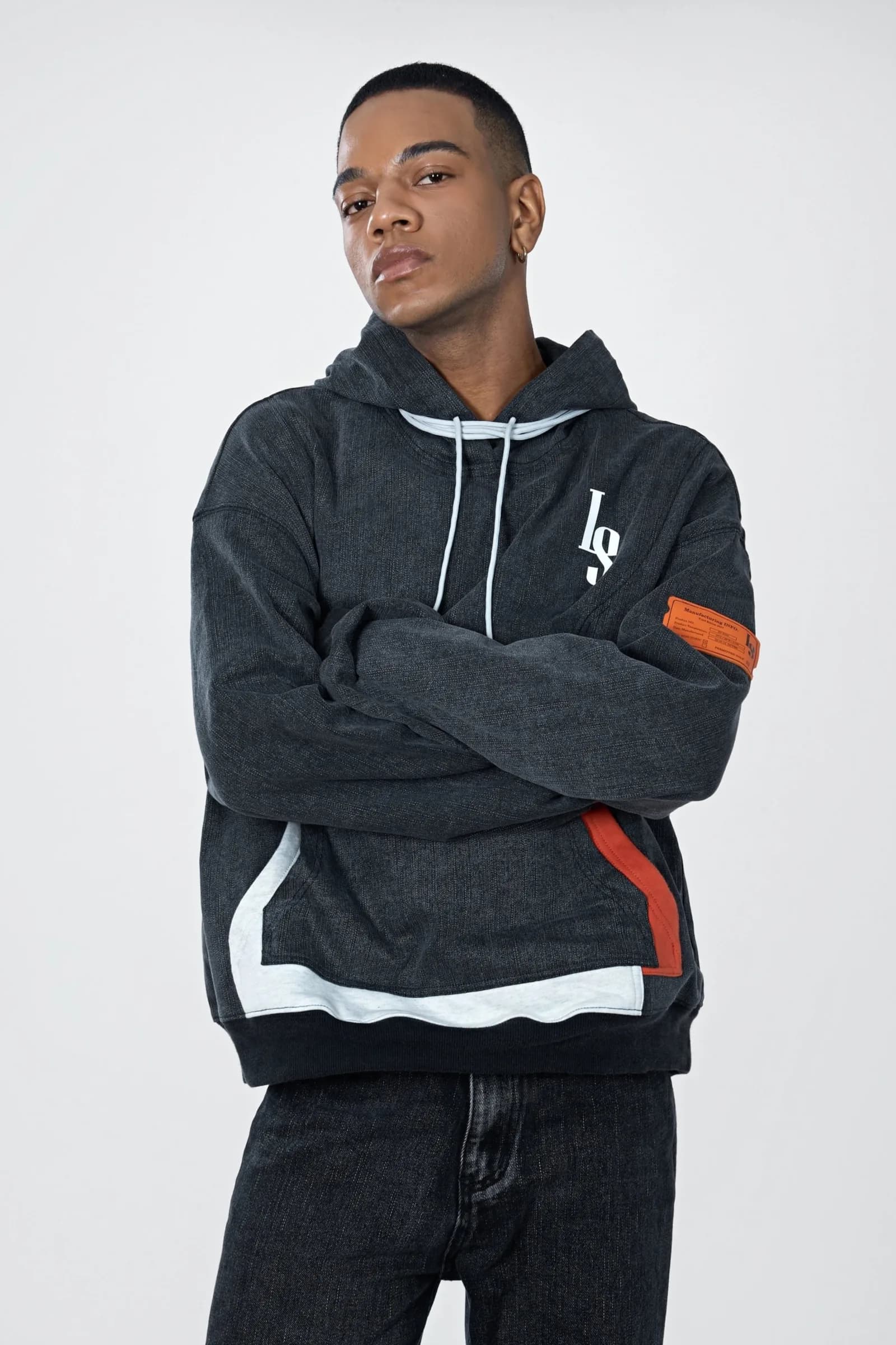 Model with arms crossed in the Denim Washed Hoodie with LS monogram, orange label and contrast hem