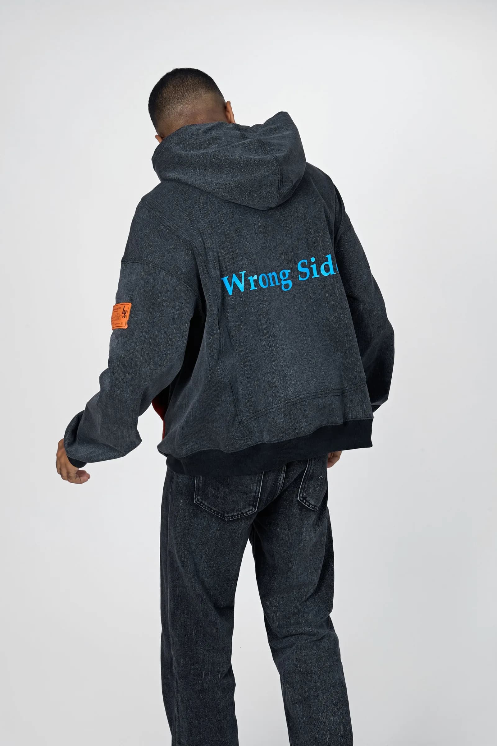 Model from behind in the Denim Washed Hoodie with “Wrong Side” printed in bright blue