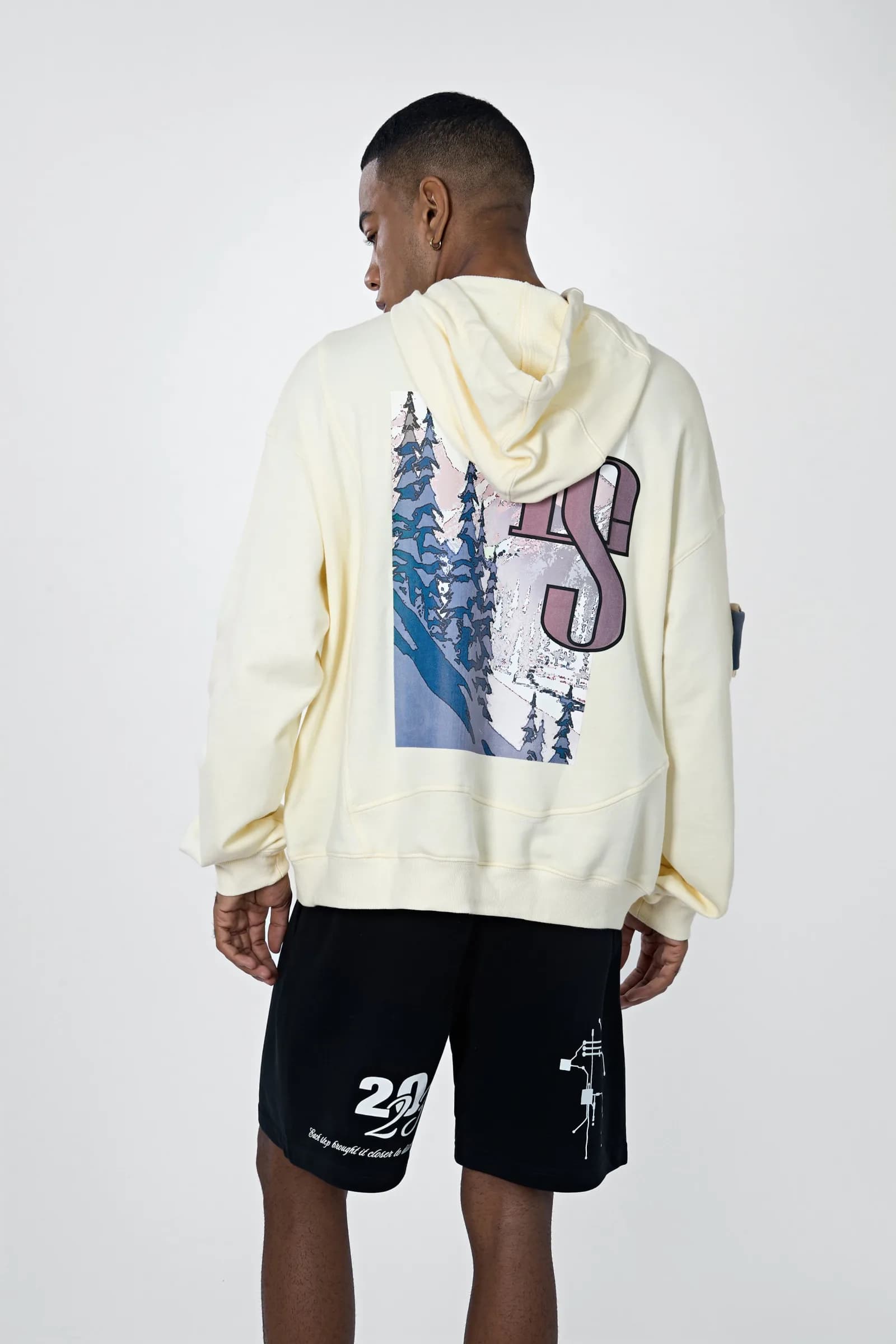 Studio shot from behind: the snow-mountain forest print framed by an oversized LS monogram
