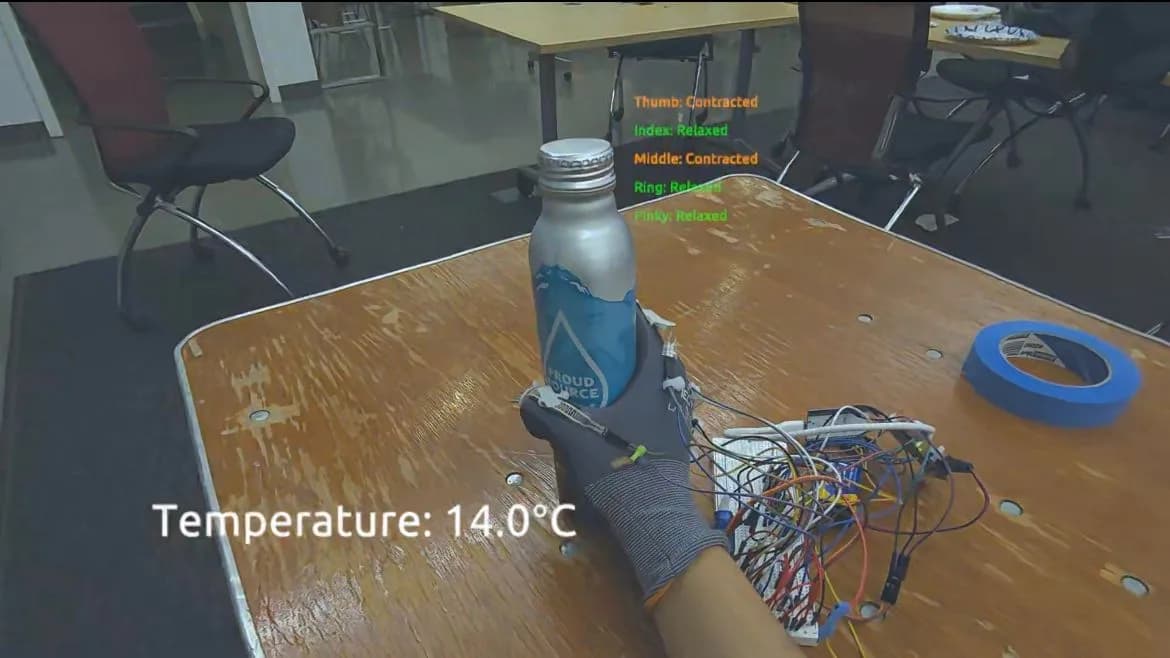 Mixed-reality passthrough view: a gloved hand grips a cold metal bottle on a table, with “Temperature: 14.0°C” at the lower left and each finger’s state listed in green and orange.