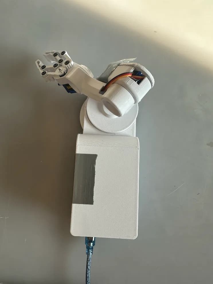 Top-down view of the finished arm with the base closed by its printed top cap and a single USB cable leaving the back