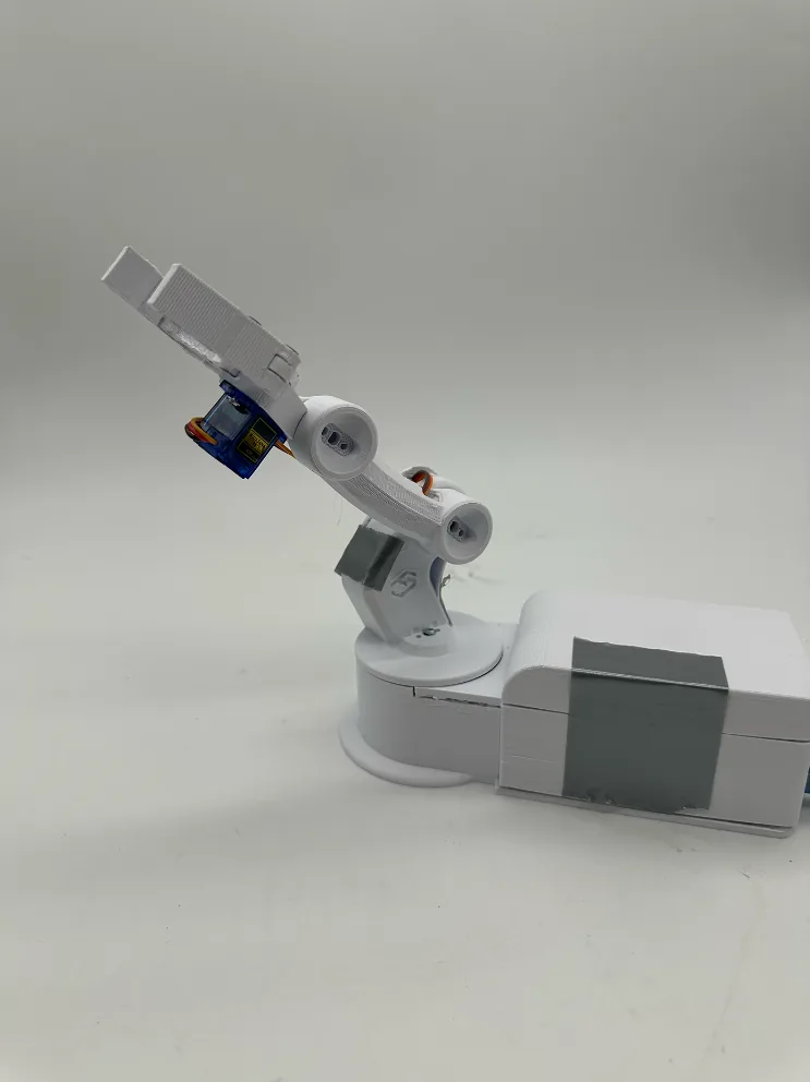 The finished arm on a grey sweep, claw raised and pointing up and forward, blue servo visible at the wrist