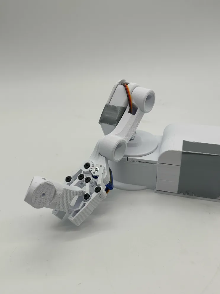 The finished arm with its claw lowered, gripping a small white printed object