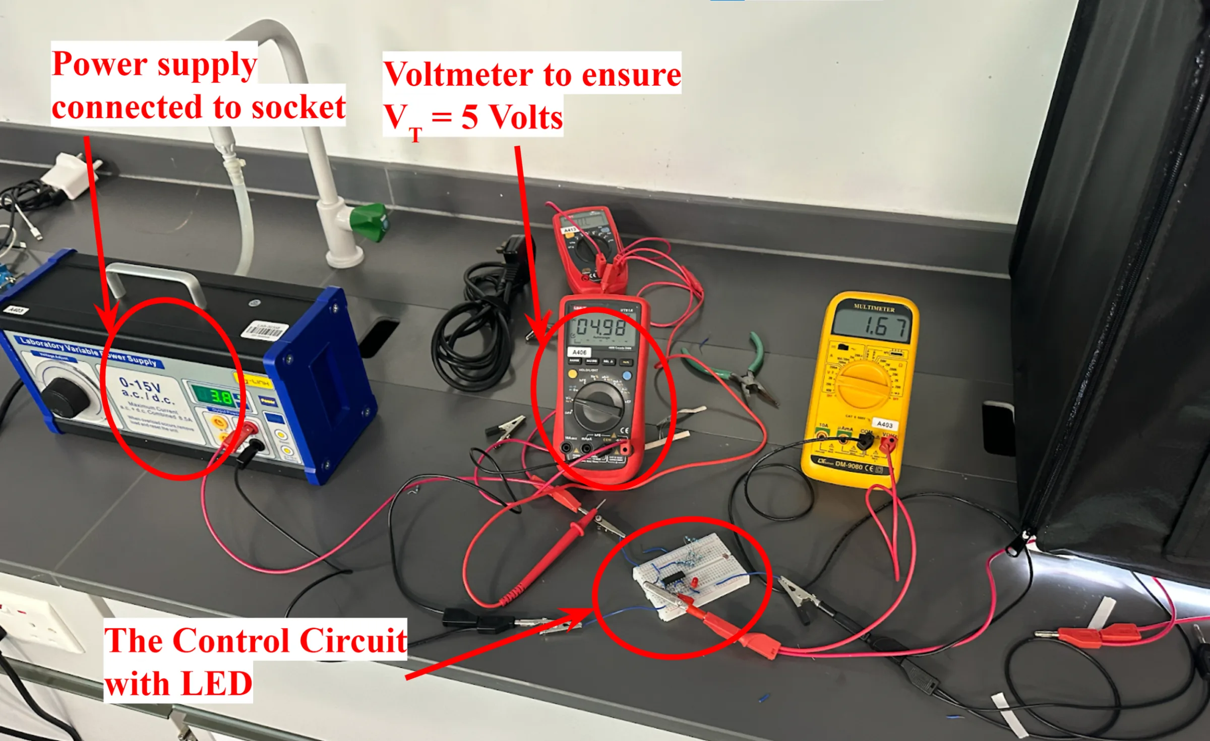 Lab bench overview, annotated: the power supply connected to the socket, a voltmeter confirming VT = 5 V (reading 4.98), and the control circuit with its LED on a small breadboard