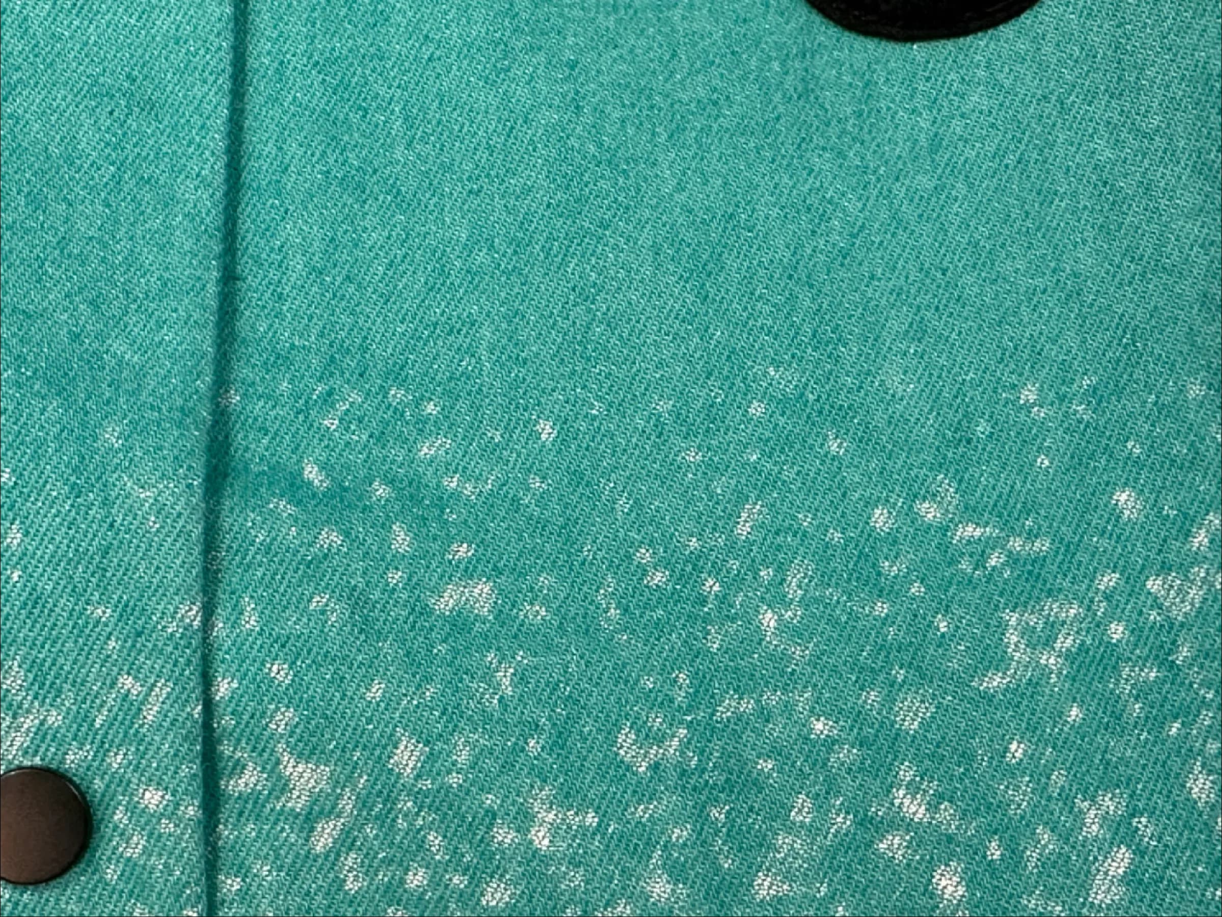 Macro photo of the faded jet-print speckle texture on the cyan denim