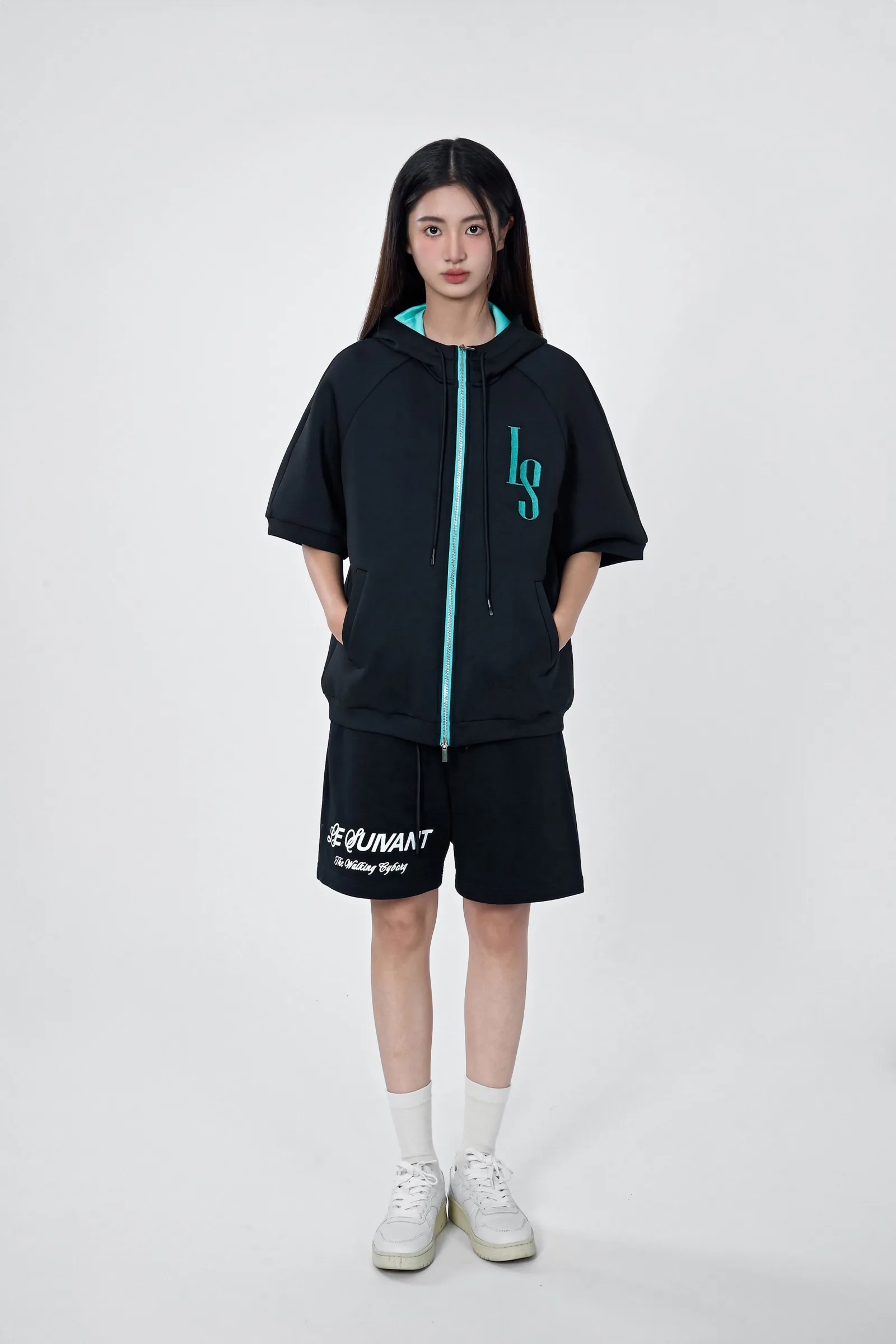 Model in the black short-sleeve embroidered Life sports jacket with a cyan zip and black shorts