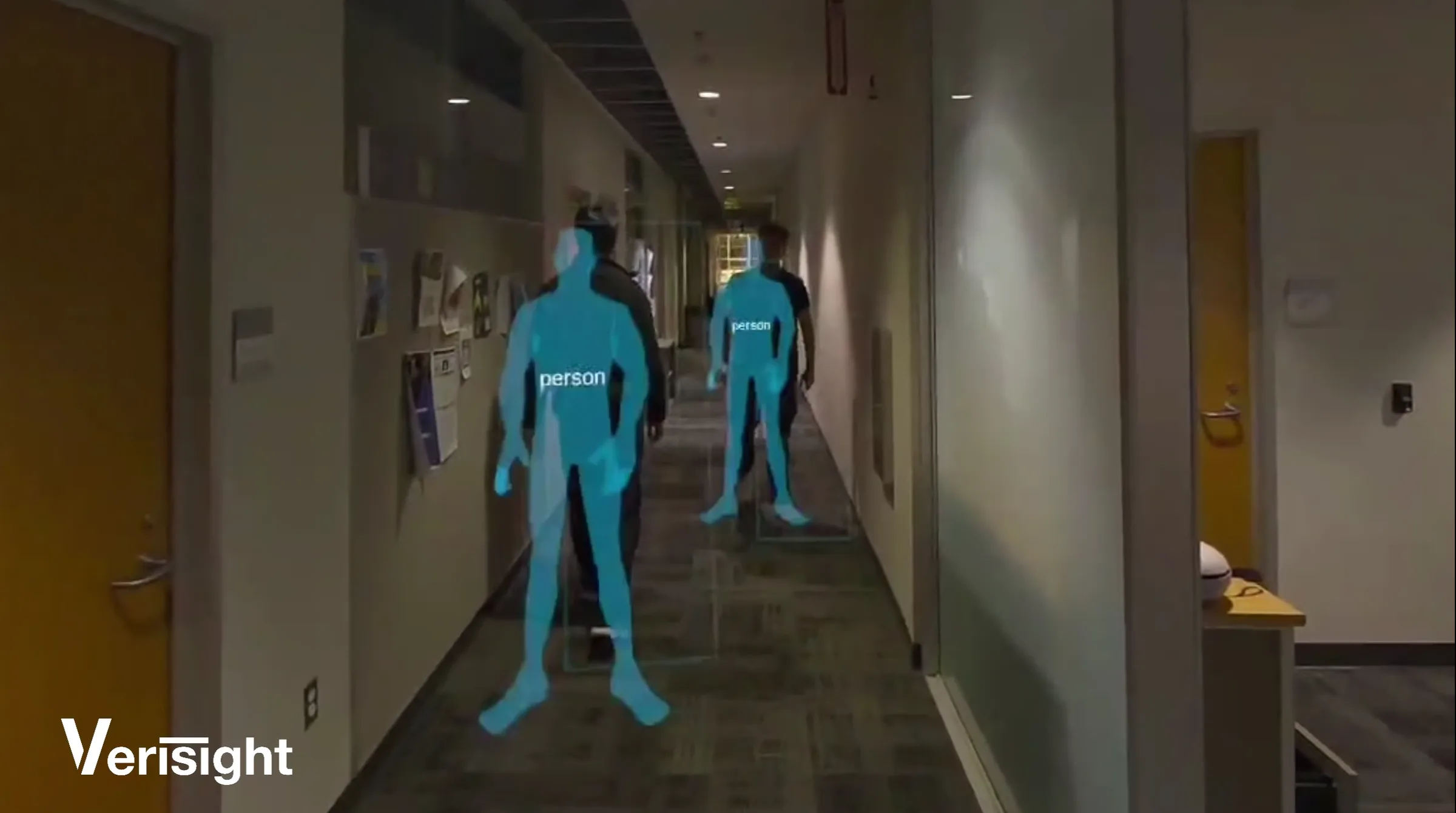 Quest 3 passthrough capture of an office hallway: two people overlaid with translucent blue silhouettes tagged “person”, VeriSight wordmark bottom-left.